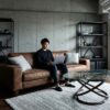 日本人の男性が住む、無骨なインダストリアルスタイルの部屋。黒や茶色だけでなく、グレーのラグやクッション、アシンメトリーなガラステーブルを取り入れ、殺風景になるのを防いでいる。
