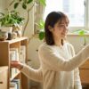 明るく整理整頓された自宅のインテリアを笑顔で整えている様子。部屋がおしゃれな人の性格や、綺麗な空間を作る心理を象徴する一枚。